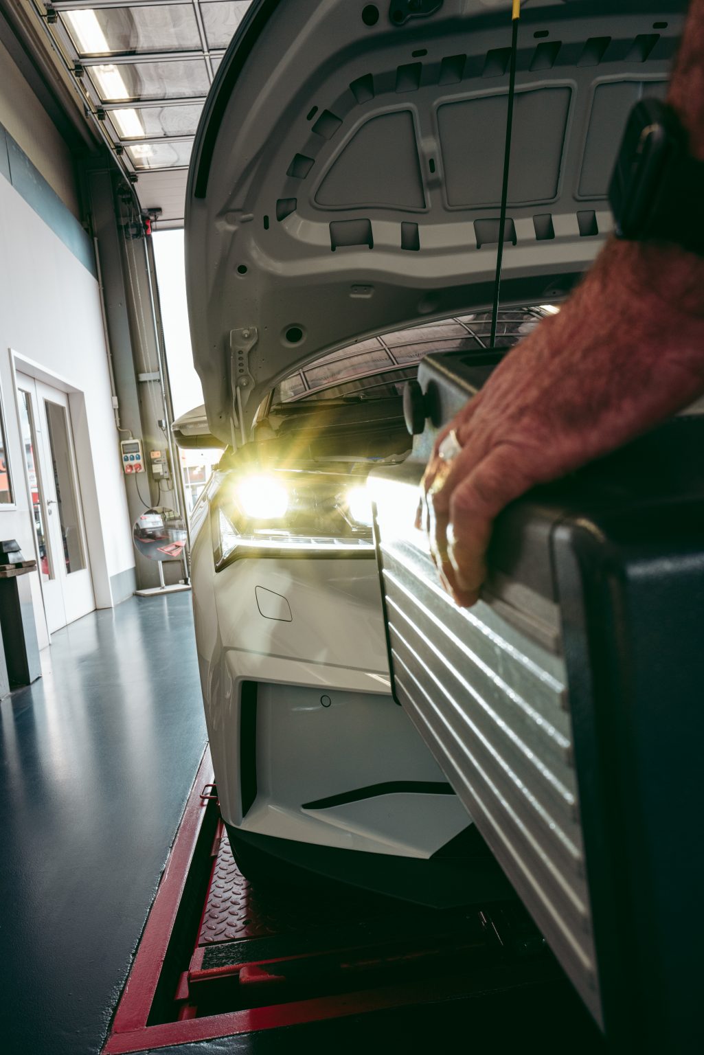 GTÜ-Prüfingenieur bei der Kontrolle der Scheinwerfer mit dem Scheinwerfereinstellgerät · Fotoshooting zur E-Mobilität beim IB Serries, Warendorf
